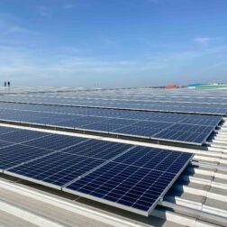 Solar panels installed on a roof of a large industrial building or a warehouse. Industrial buildings in the background. Horizontal photo.